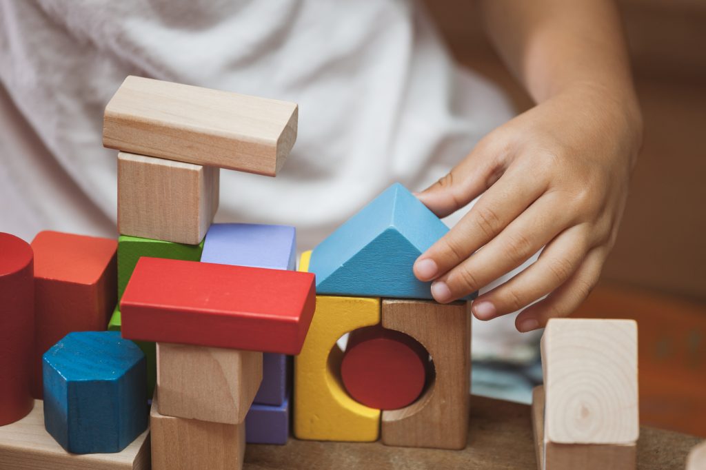 Focus on child&rsquo;s hand  playing with colorful wooden blocks in vintage color tone